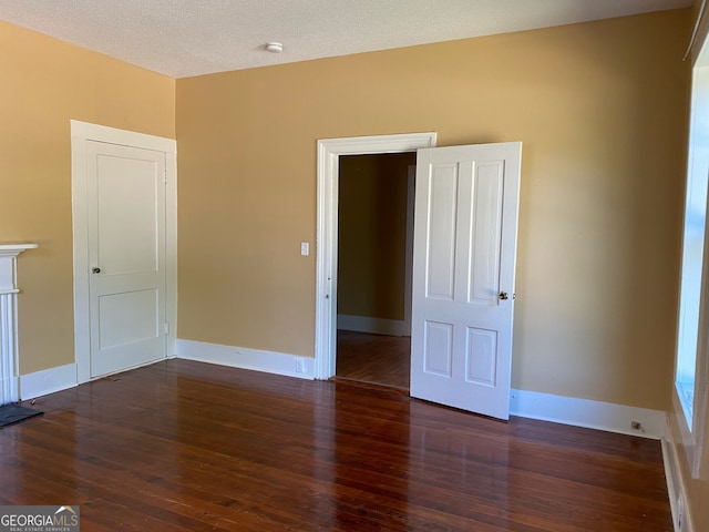 empty room featuring a textured ceiling and dark wood-type flooring