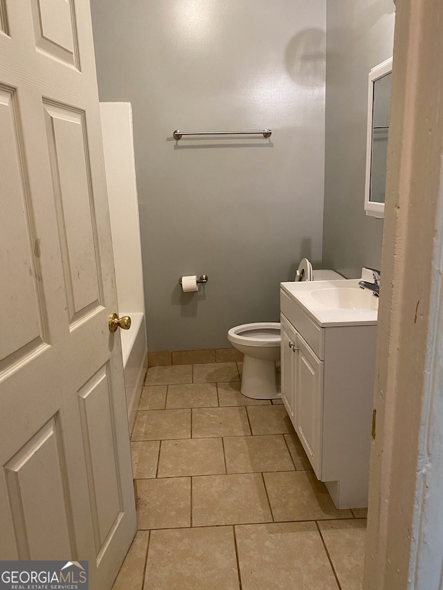 bathroom featuring vanity, toilet, a tub to relax in, and tile patterned flooring