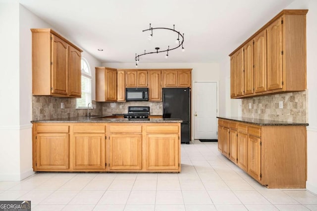 kitchen featuring decorative backsplash, dark stone counters, light tile patterned flooring, black appliances, and sink