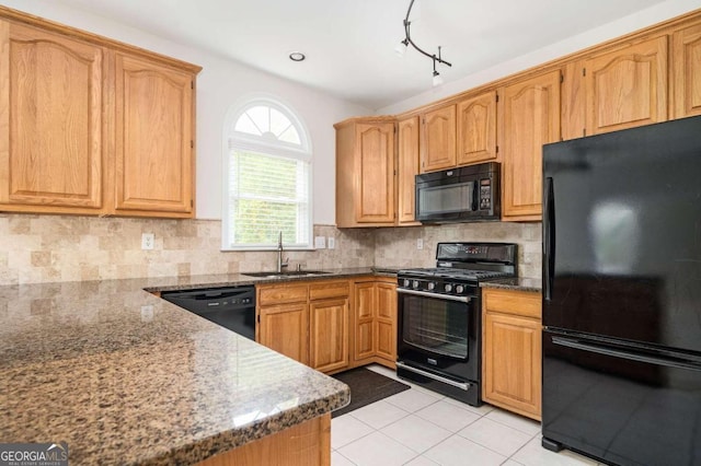 kitchen with light tile patterned floors, backsplash, dark stone countertops, black appliances, and sink