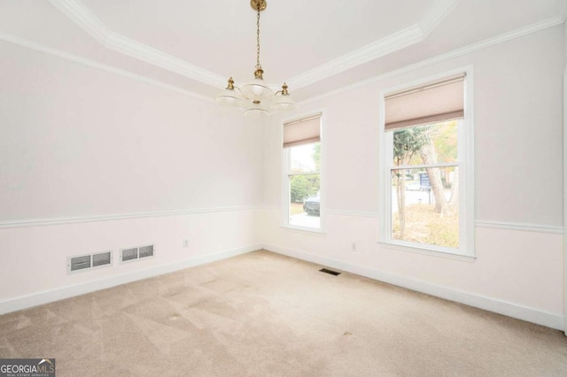 carpeted empty room with crown molding, a tray ceiling, and an inviting chandelier