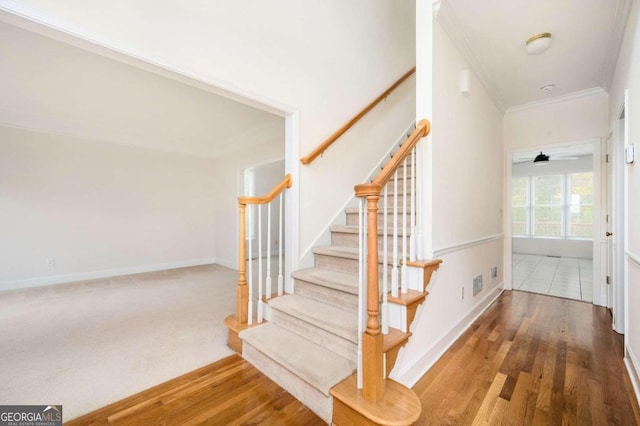 stairway with crown molding, hardwood / wood-style floors, and ceiling fan