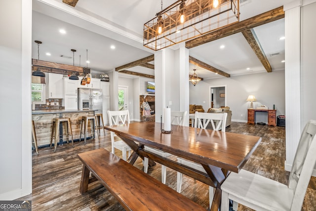 dining room with dark hardwood / wood-style flooring, beamed ceiling, and a stone fireplace