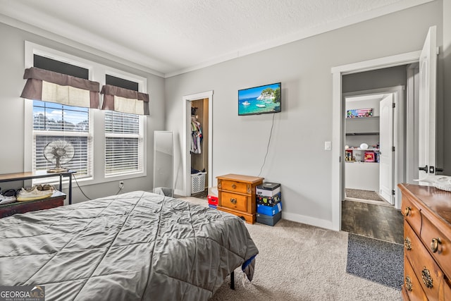 bedroom featuring a walk in closet, carpet, a textured ceiling, and a closet