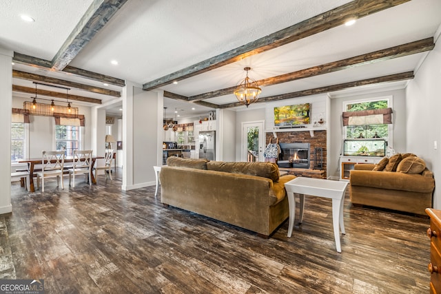 living room with beamed ceiling, a textured ceiling, a healthy amount of sunlight, and dark hardwood / wood-style floors