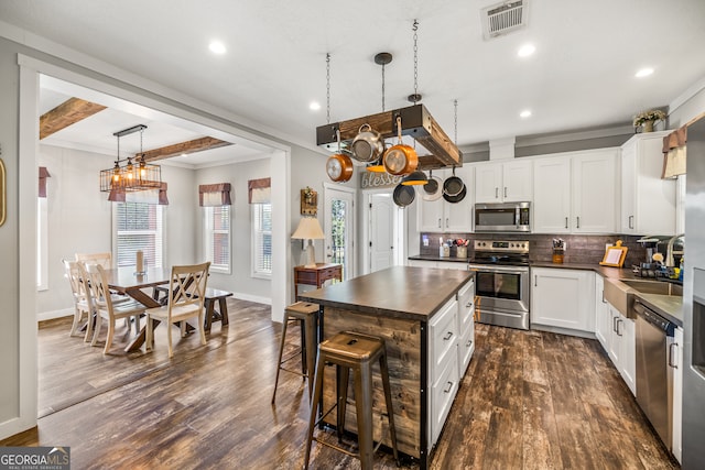 kitchen with stainless steel appliances, beamed ceiling, white cabinets, and dark wood-type flooring