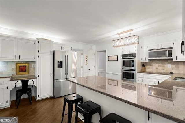 kitchen featuring white cabinetry, appliances with stainless steel finishes, dark stone countertops, and dark hardwood / wood-style flooring