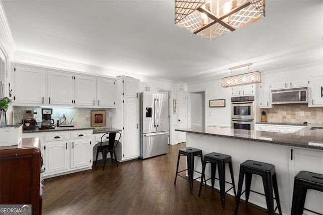 kitchen featuring stainless steel appliances, backsplash, a kitchen breakfast bar, white cabinets, and dark wood-type flooring