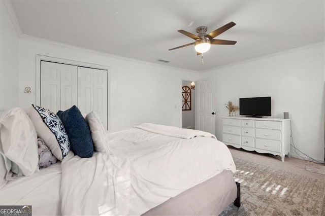 carpeted bedroom featuring ornamental molding, ceiling fan, and a closet