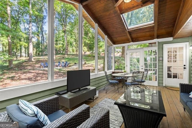 sunroom / solarium with vaulted ceiling with skylight, ceiling fan, wood ceiling, and french doors