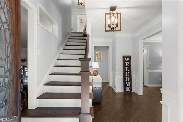 entrance foyer with dark hardwood / wood-style flooring, an inviting chandelier, and crown molding