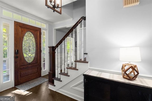 entryway featuring ornamental molding, dark wood-type flooring, a healthy amount of sunlight, and an inviting chandelier