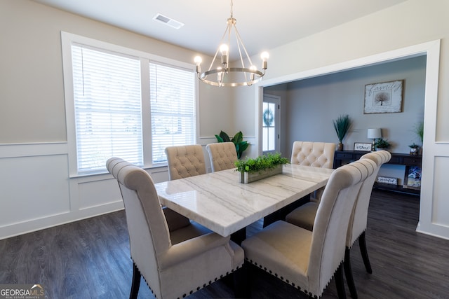 dining area with dark wood-type flooring and an inviting chandelier