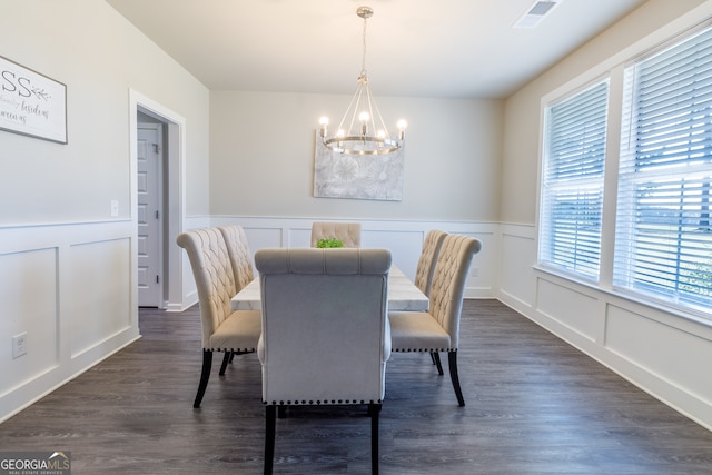 dining area with dark wood-type flooring and an inviting chandelier