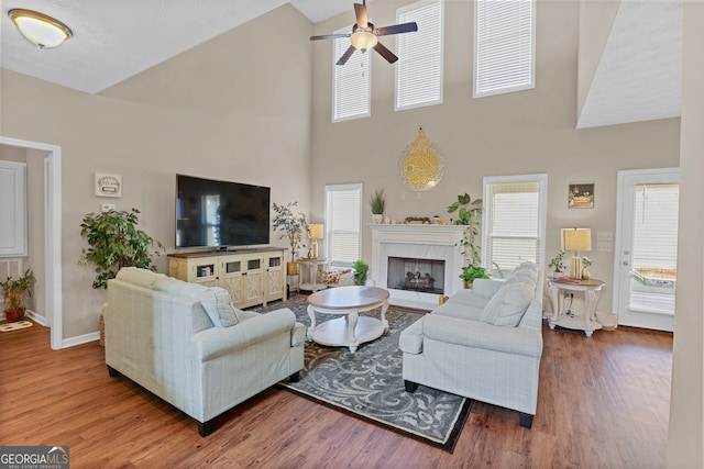 living room featuring a premium fireplace, hardwood / wood-style floors, high vaulted ceiling, and ceiling fan