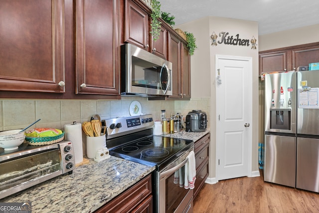 kitchen with backsplash, appliances with stainless steel finishes, a textured ceiling, light stone countertops, and light hardwood / wood-style flooring