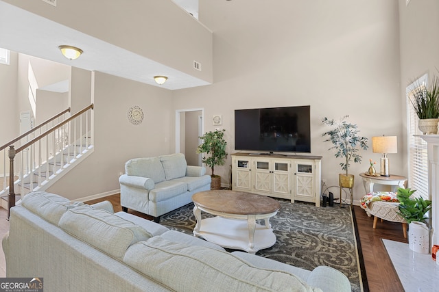 living room featuring a high end fireplace, hardwood / wood-style flooring, and a towering ceiling