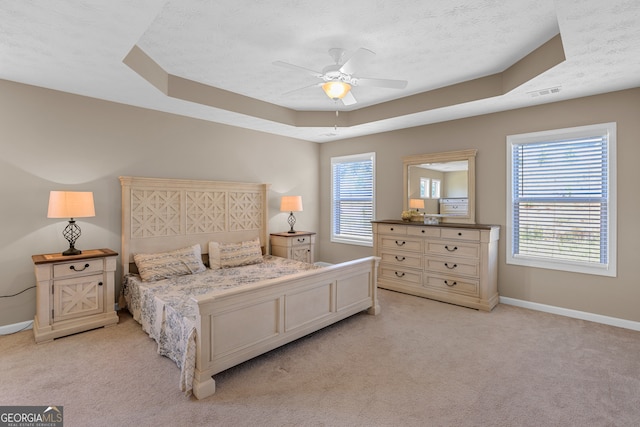 carpeted bedroom with ceiling fan, a raised ceiling, and a textured ceiling