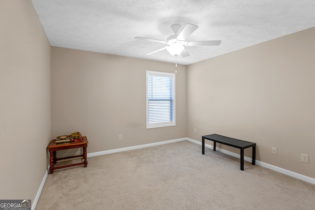 empty room with light carpet, a textured ceiling, and ceiling fan