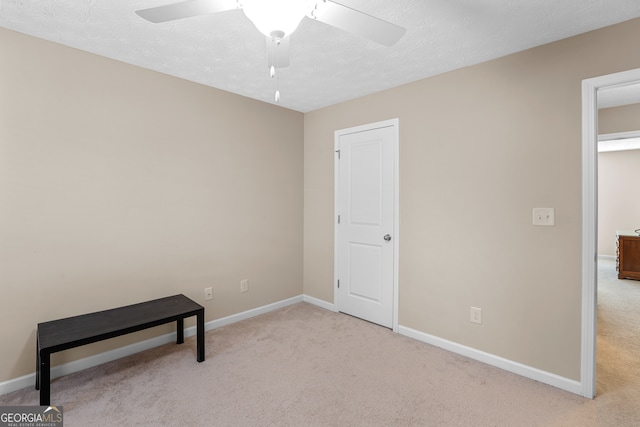 unfurnished bedroom featuring ceiling fan, a textured ceiling, and light colored carpet