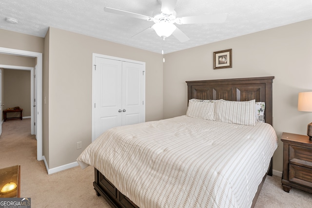 bedroom featuring a closet, ceiling fan, light carpet, and a textured ceiling