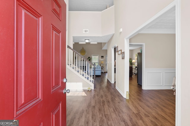 foyer featuring crown molding, a towering ceiling, and dark hardwood / wood-style floors