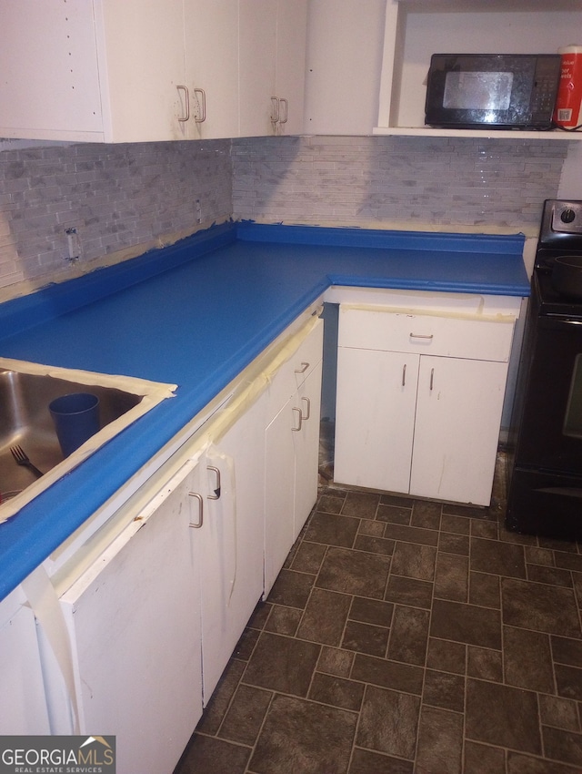 kitchen featuring decorative backsplash, white cabinetry, sink, and black electric range