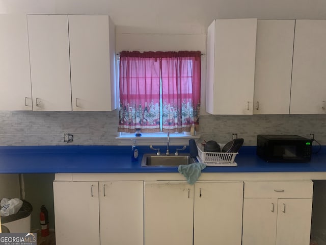 kitchen with tasteful backsplash, sink, and white cabinets