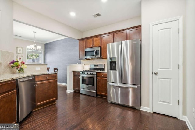 kitchen featuring pendant lighting, dark wood-type flooring, light stone countertops, appliances with stainless steel finishes, and a notable chandelier