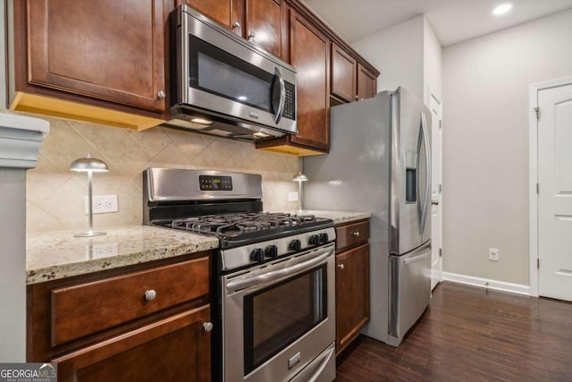 kitchen featuring tasteful backsplash, light stone countertops, dark hardwood / wood-style floors, and appliances with stainless steel finishes