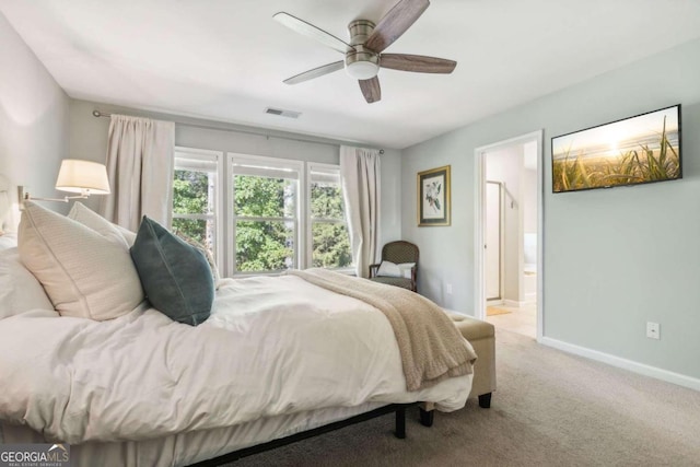 bedroom featuring ceiling fan, light carpet, and ensuite bath