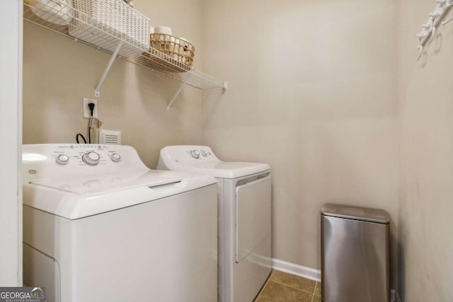 laundry area with dark tile patterned floors and washing machine and clothes dryer