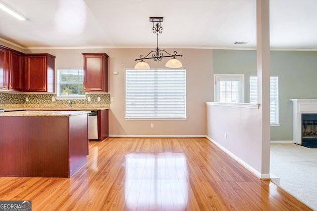 kitchen with backsplash, hanging light fixtures, light hardwood / wood-style floors, and plenty of natural light