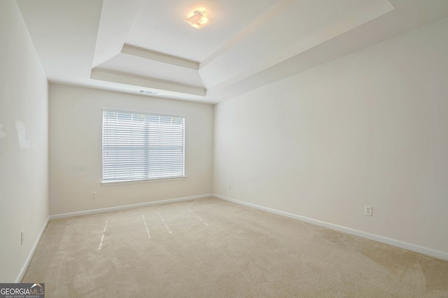 carpeted spare room with a tray ceiling