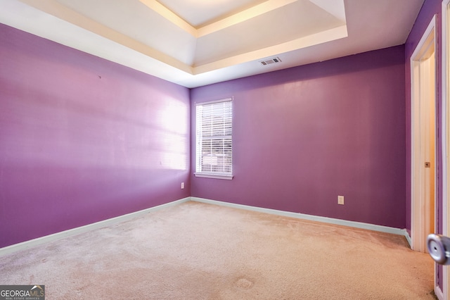 carpeted spare room with a tray ceiling