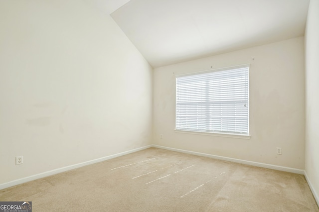 carpeted spare room featuring vaulted ceiling