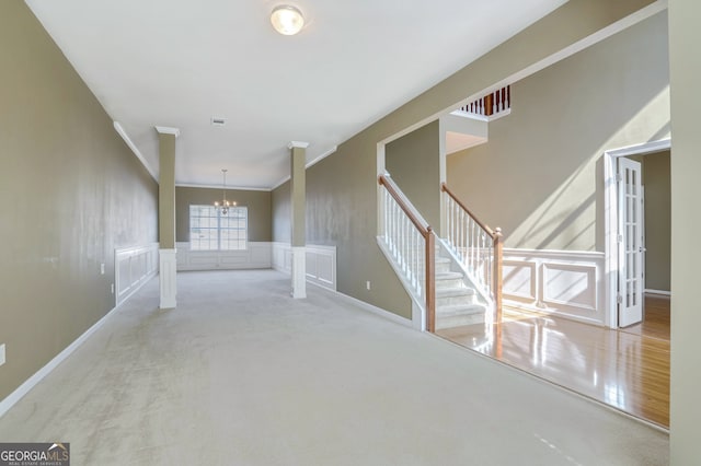 corridor with crown molding, a notable chandelier, and light colored carpet