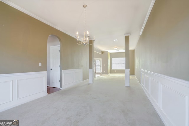 spare room featuring ornamental molding, carpet floors, and a chandelier