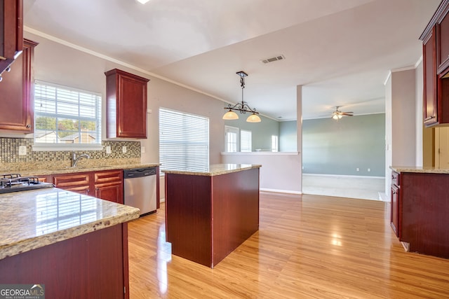 kitchen with appliances with stainless steel finishes, light wood-type flooring, a center island, hanging light fixtures, and decorative backsplash