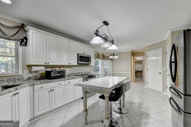 kitchen with hanging light fixtures, white cabinetry, stainless steel appliances, light stone counters, and ornamental molding