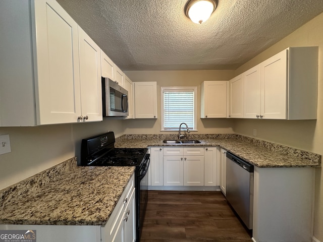 kitchen featuring dark wood-type flooring, stainless steel appliances, sink, white cabinets, and light stone counters