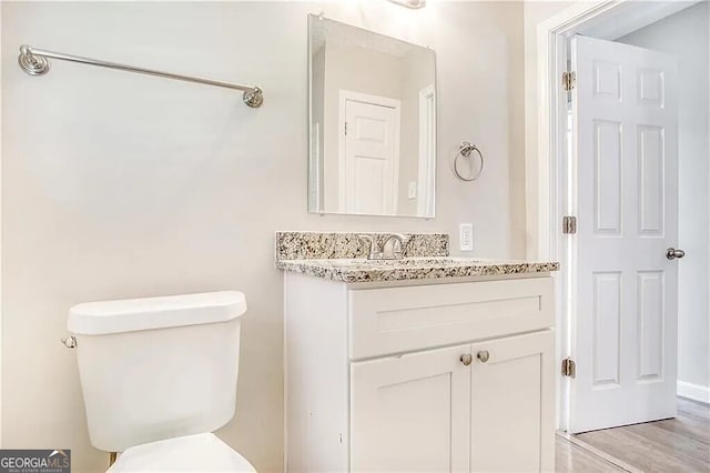 bathroom with toilet, hardwood / wood-style floors, and vanity