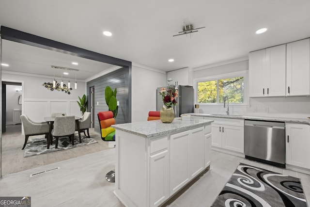 kitchen with white cabinets, a center island, stainless steel dishwasher, and sink