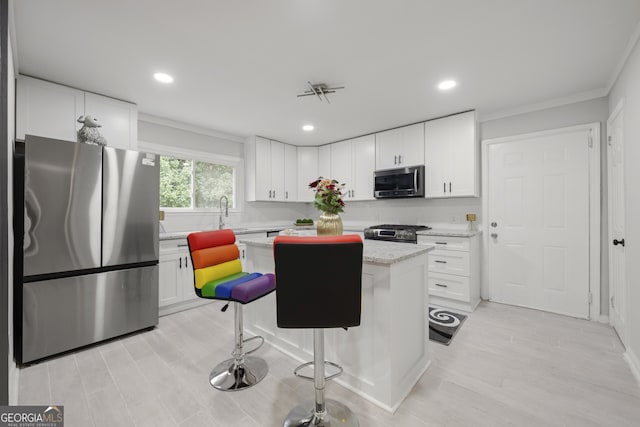 kitchen featuring white cabinetry, light stone counters, a kitchen bar, a kitchen island, and appliances with stainless steel finishes