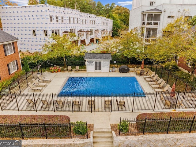 view of swimming pool featuring a patio area and a storage unit