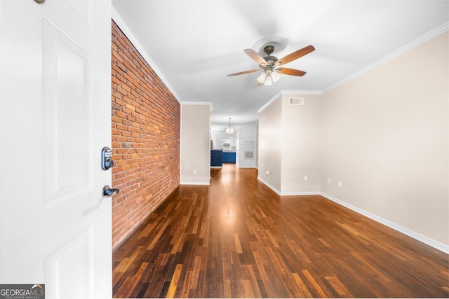 unfurnished living room featuring crown molding, ceiling fan, brick wall, and dark hardwood / wood-style flooring