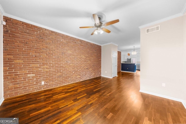 unfurnished living room with ceiling fan with notable chandelier, crown molding, brick wall, and dark hardwood / wood-style floors