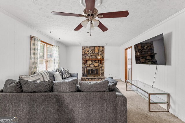 carpeted living room featuring ceiling fan, a textured ceiling, ornamental molding, and a fireplace