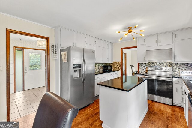 kitchen with wall chimney range hood, white cabinets, light wood-type flooring, stainless steel appliances, and a center island