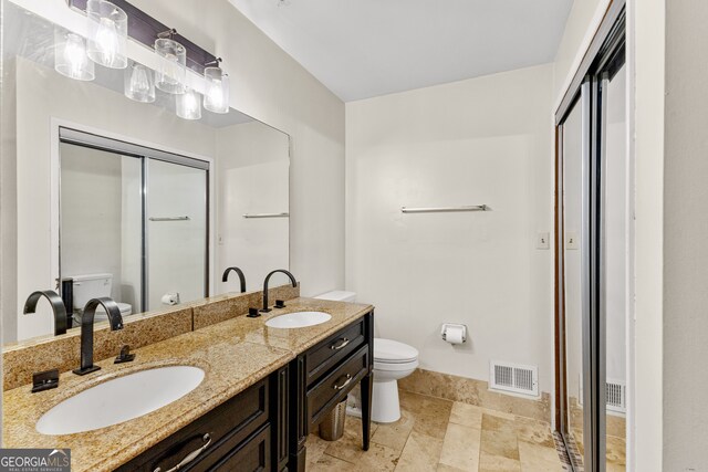 bathroom featuring toilet, a shower with shower door, and vanity